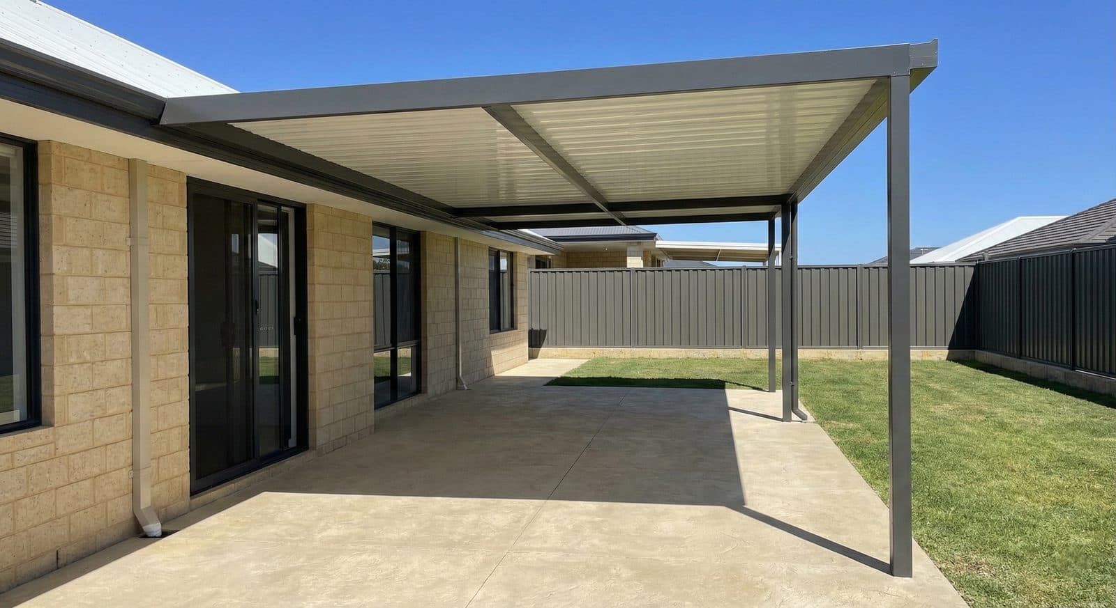 Flat roof patio with a dark steel frame over a concrete alfresco beside a manicured lawn in Perth, WA