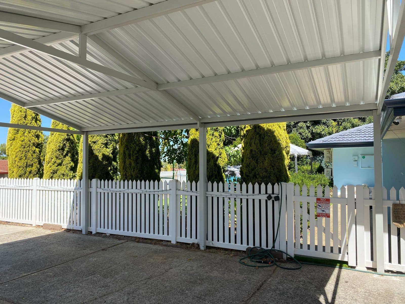 Flat roof verandah with a white picket fence and established garden at a Perth home
